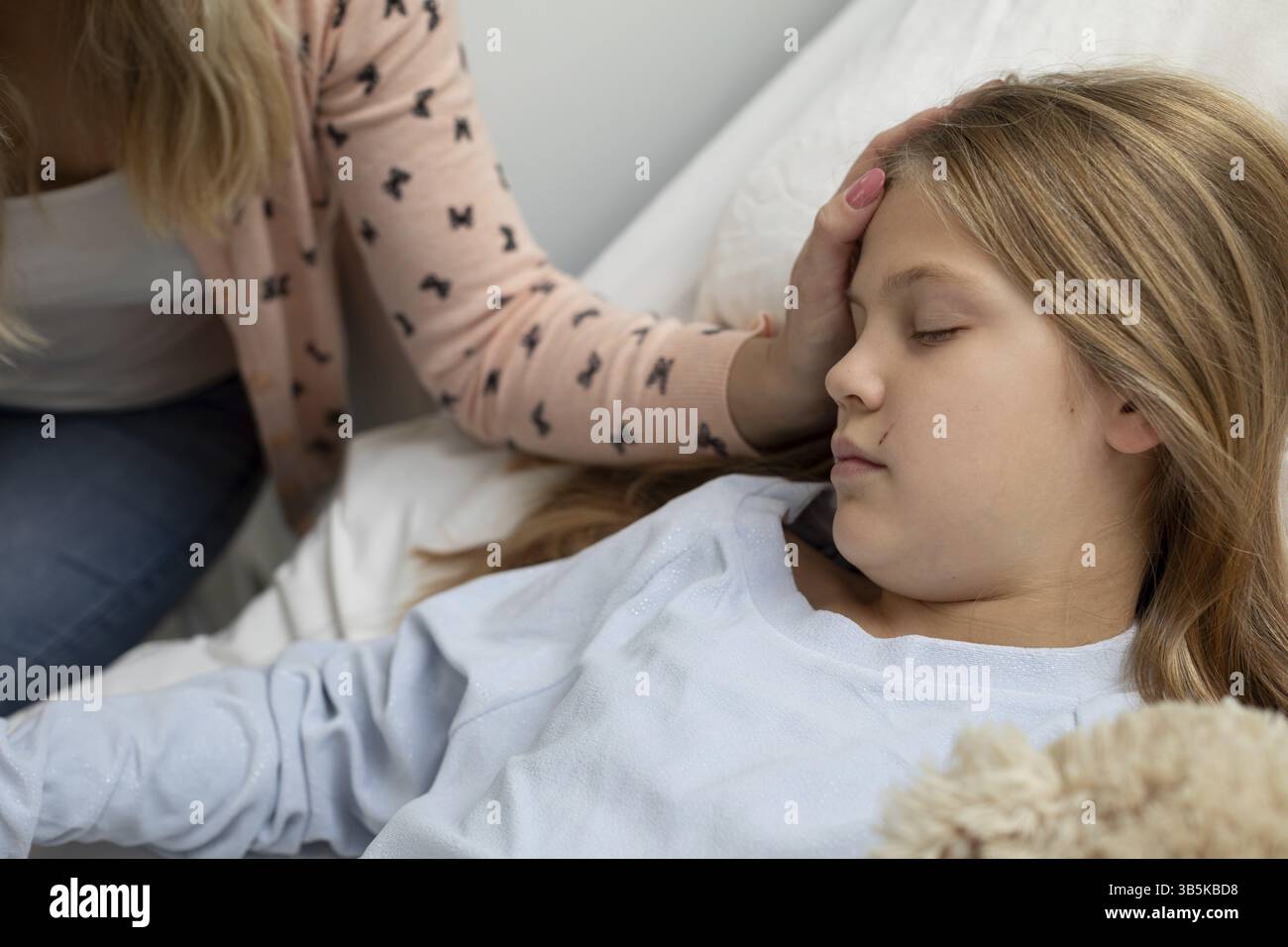 Eine Mutter kümmert sich liebevoll um ihre kranke Tochter im Bett, zeigt tiefes Mitgefühl und unerschütterliche Unterstützung Stockfoto