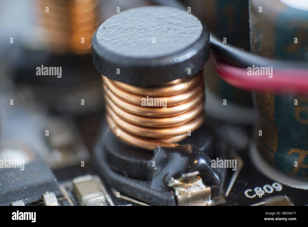 Eine staubige Computerkomponente. Detail einer staubigen Computerplatine. Elektrolytkondensator und Leiter sichtbar auf der Leiterplatte. Selektiv Stockfoto