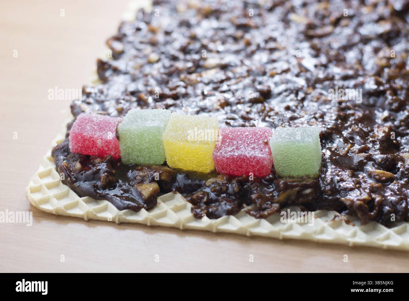Schokolade topping mit wallnuts auf Kuchen Kruste für gerollte Schokoladenkuchen mit Gelee Bonbons Stockfoto