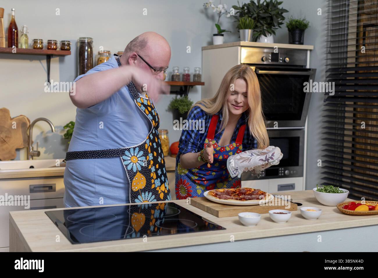 Eine fröhliche Kochszene mit zwei Personen, die zusammen mit Enthusiasmus und Glück eine köstliche Mahlzeit kreieren Stockfoto
