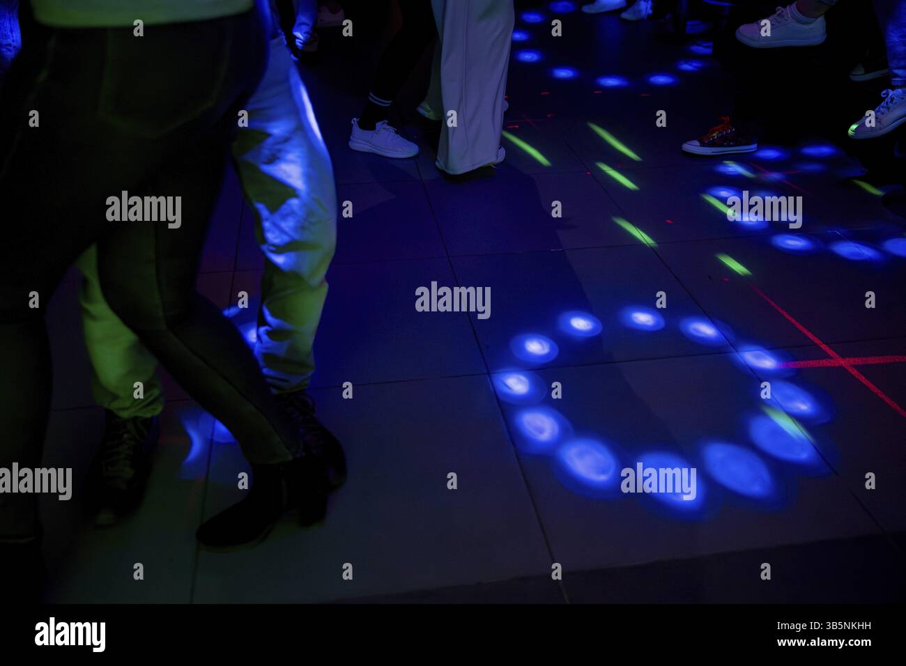 Eine lebendige Tanzszene mit farbenfrohen Lichtern, die den energiegeladenen Tanzboden mit lebhaften Bewegungen beleuchten Stockfoto