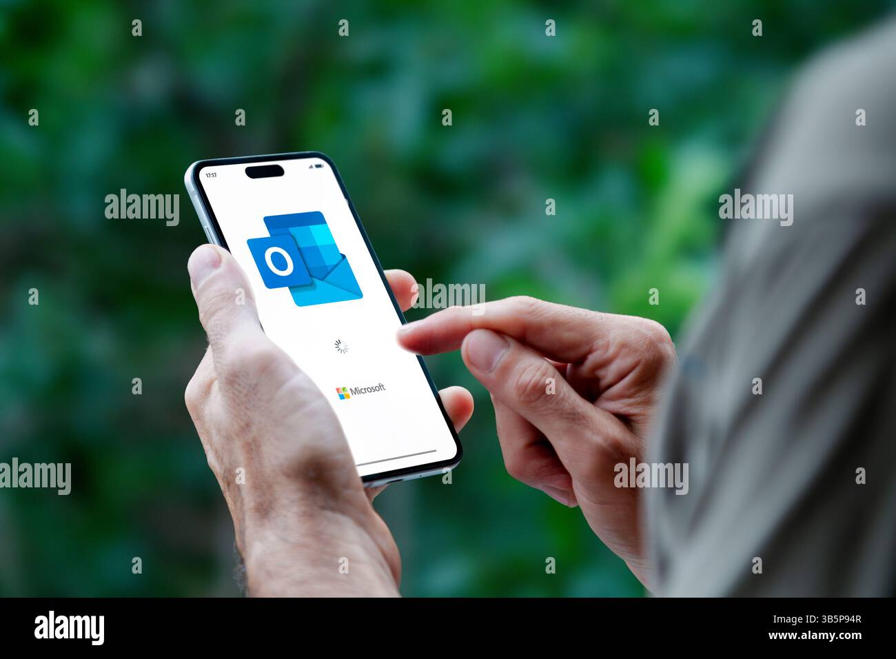 Mann, der ein Mobiltelefon hält und die Outlook-App für E-Mails von Microsoft öffnet. ROSARIO, ARGENTINIEN - 30. APRIL 2025. Stockfoto