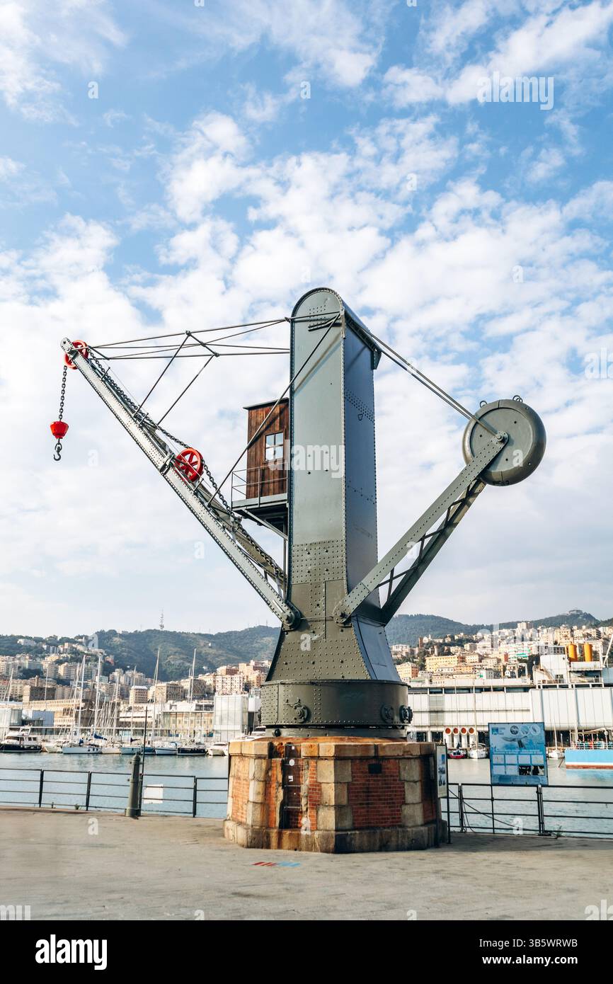 Genua, Italien - 22. September 2024: Historischer Industriekran steht an der Uferpromenade des alten Hafens mit Blick auf die Stadt und den Yachthafen. Stockfoto