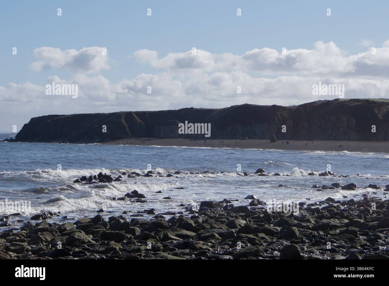 Felsige Küste mit Wellen und Klippen im Hintergrund entlang der Küste. Seaham Beach, England Stockfoto