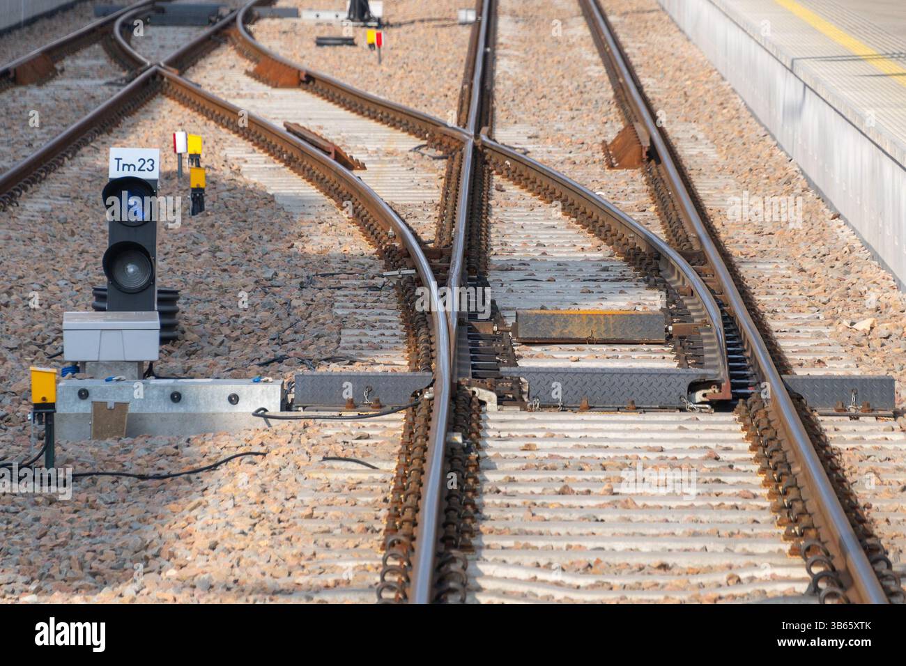 Bahnschalter mit sich kreuzenden Gleisen, Kiesbett, Signalleuchte, Schaltkästen und präziser Schienenausrichtung. Eisenbahnverkehr Stockfoto