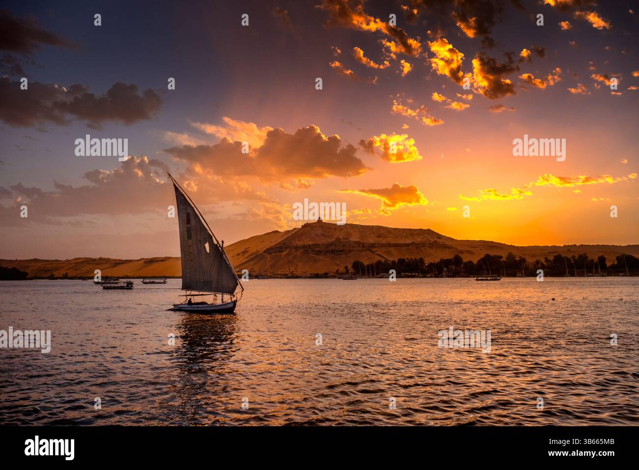 Felucca-Segelboot gleitet bei Sonnenuntergang auf dem Nil in Assuan, Ägypten. Stockfoto