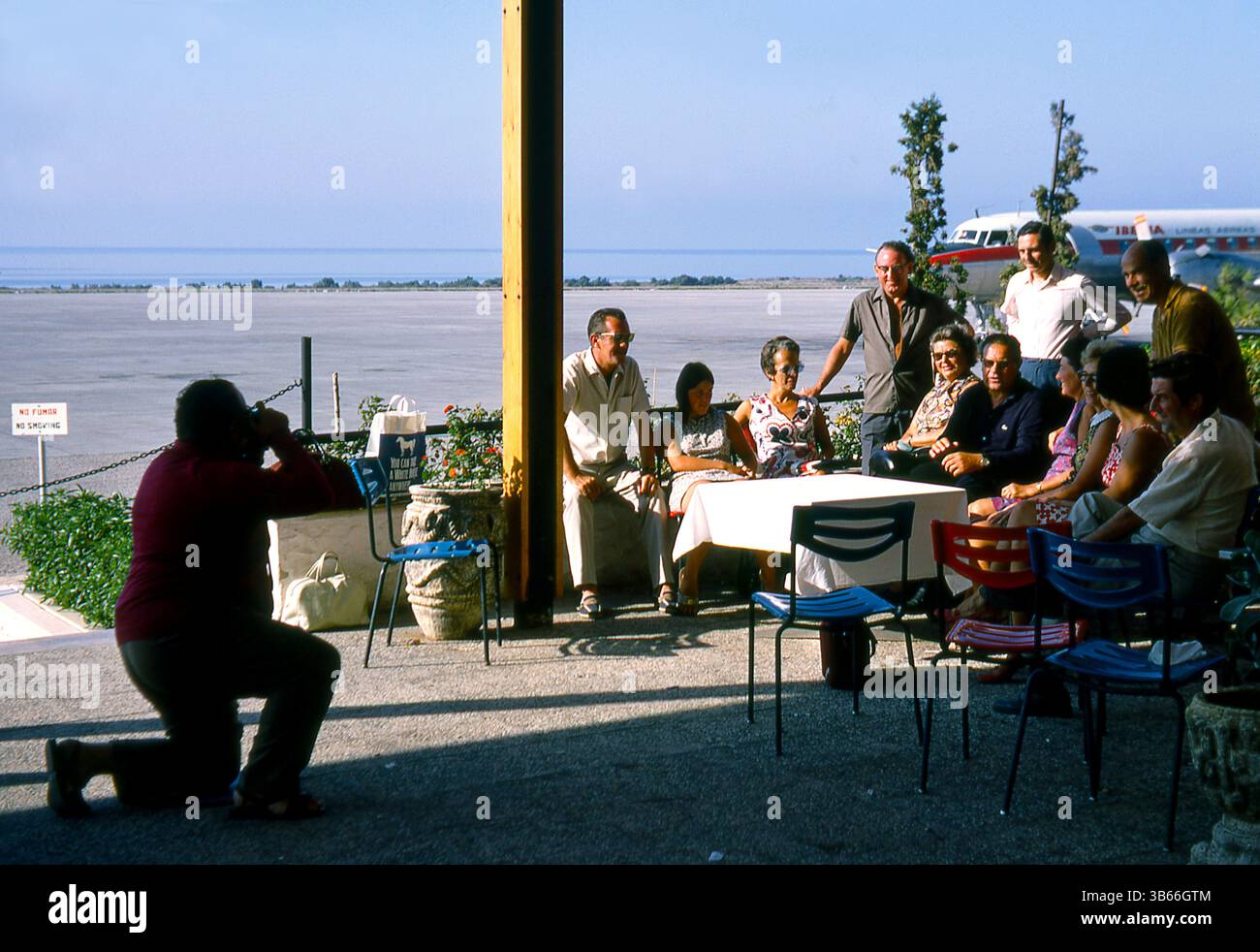 Eine Gruppe von Touristen, die sich 1969 im Außenbereich des Flughafens Almeria, Spanien, für ein Foto ausgeben - im Hintergrund befindet sich ein Iberia Airlines Convair CV 440 Stockfoto