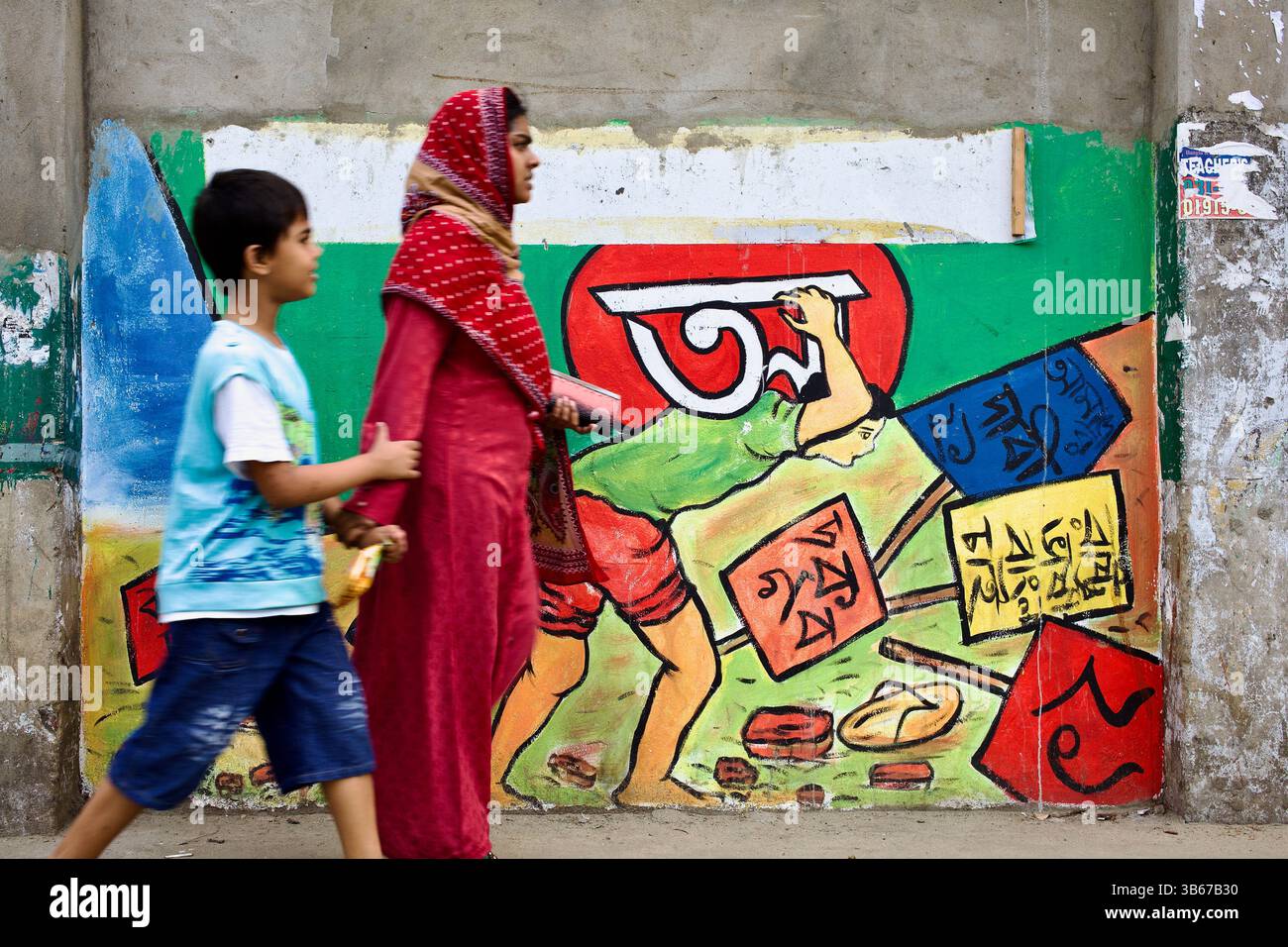 Frau und Kind gehen an einem Wandgemälde in Chittagong vorbei, das an die Sprachbewegung von 1952 erinnert, die von männlichen Symbolen des nationalistischen Kampfes dominiert wird. Stockfoto