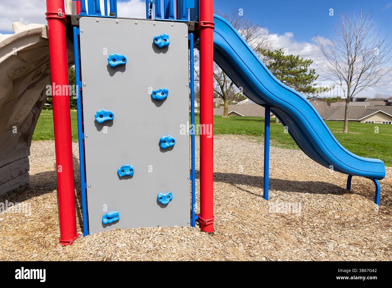 Blaue, rote und graue Spielplatzausrüstung - Rutsche und Kletterwand Stockfoto