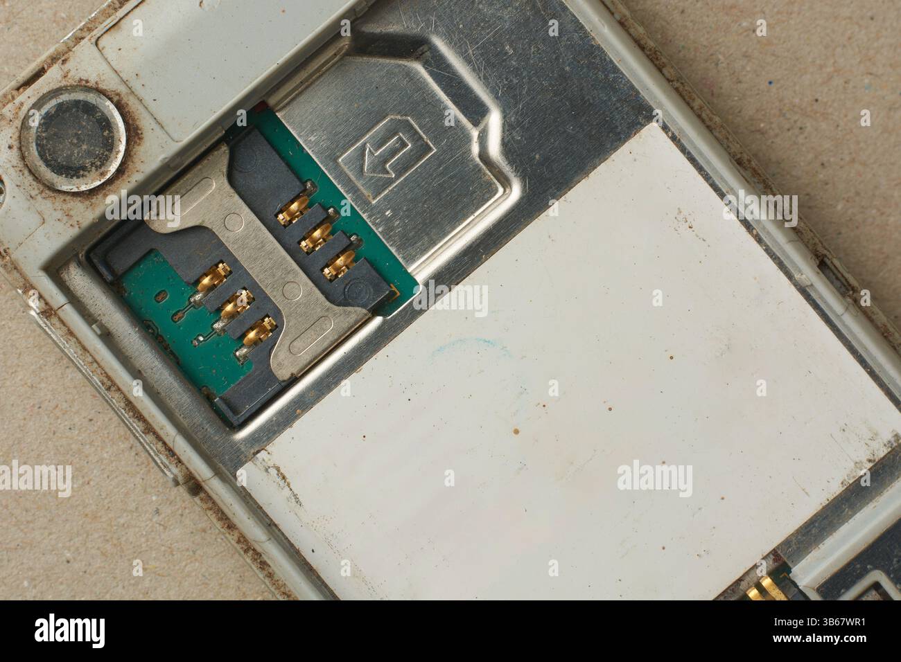 Nahaufnahme des Mini-SIM-Kartensteckplatzes des alten schmutzigen, veralteten Mobiltelefons, entfernte Rückabdeckung und Batterie des Mobiltelefons, direkt von oben Stockfoto