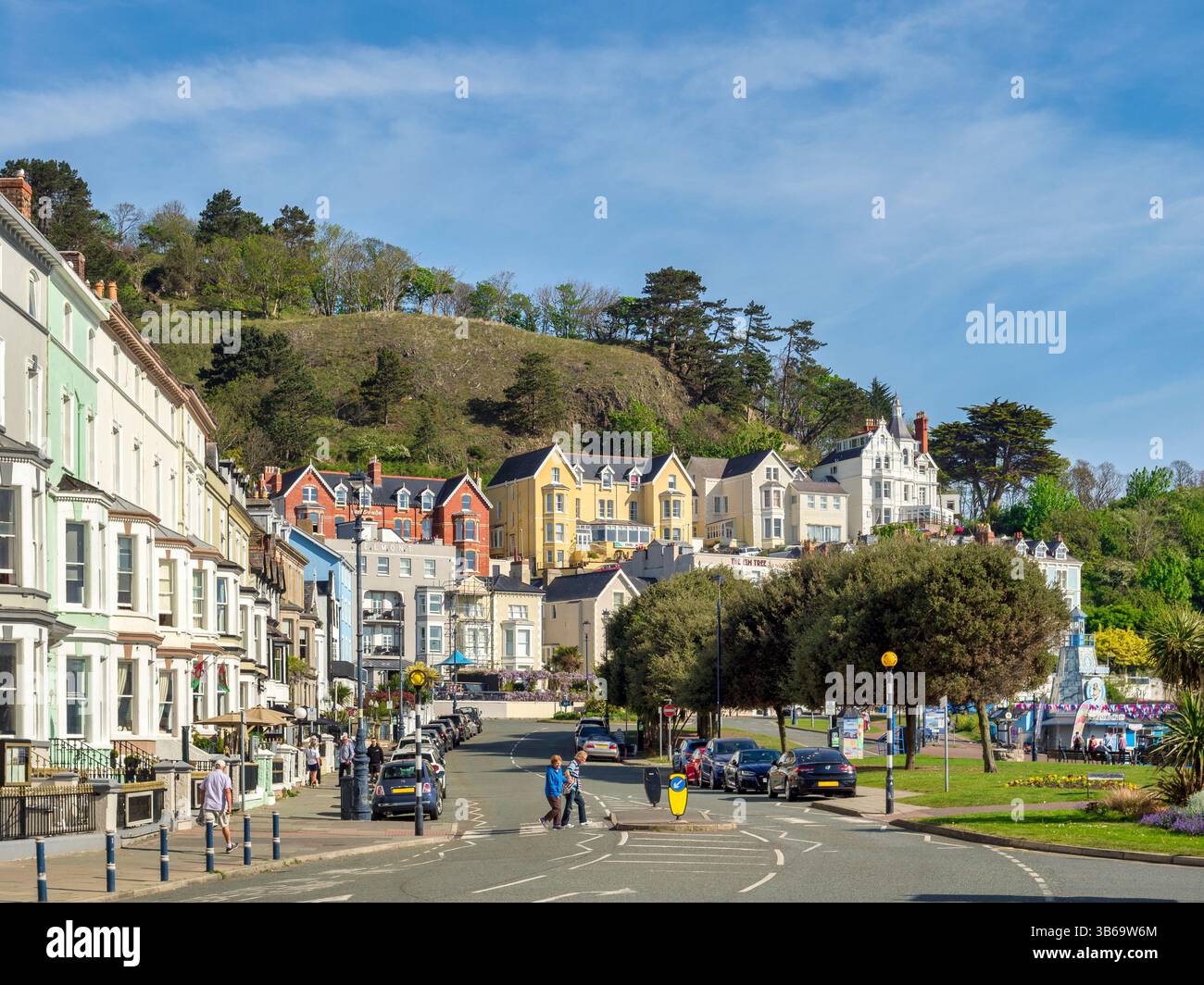 Hotels am Meer in North Parade, Llandudno, North Wales, Großbritannien, People, parkende Autos und Attraktionen am Meer an einem hellen Frühlingsmorgen. Stockfoto