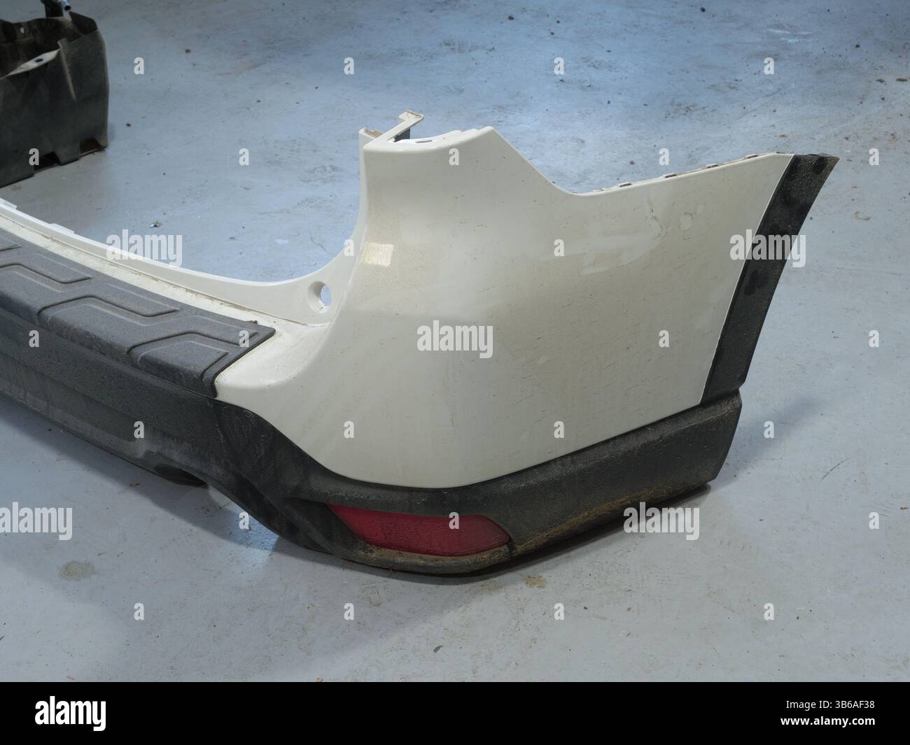 Abgenommene, weiße Stoßfängerabdeckung des Fahrzeugs weist gewisse Abnutzungserscheinungen auf, die durch Verwendung oder Lagerung verursacht werden können. Stockfoto