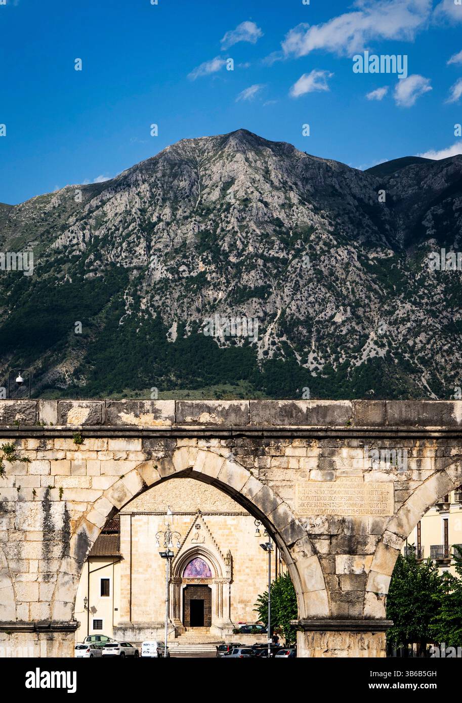 Eine malerische Aussicht mit einem alten Steinbogen im Vordergrund, der zu einem bezaubernden Stadtplatz mit einem historischen Gebäude führt. Im Hintergrund wird A angezeigt Stockfoto
