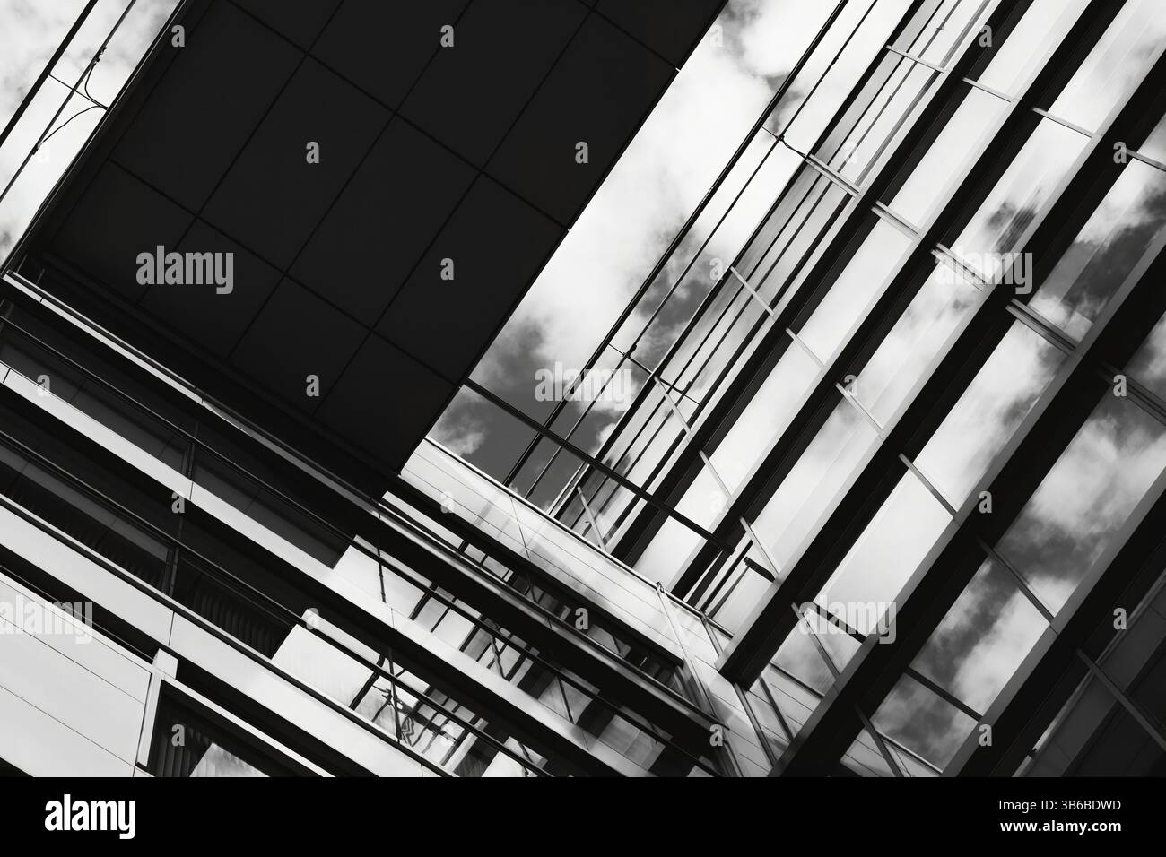 Schwarzweißes modernes Glasgebäude von unten betrachtet, abstrakte Geometrie und Linien, starker Kontrast und leichtes Spiel Stockfoto