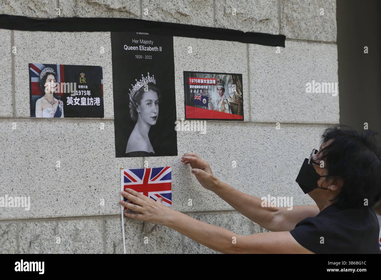 12. September 2022, HONGKONG, CHINA: Eine Frau, die versucht, den kleinen Union Jack an die Außenwand des britischen Generalkonsulats in Hongkong zu kleben, als Geste des Respekts für Großbritannien und die verstorbene Königin Elizabeth II. September 2022 Hong Kong.ZUMA/Liau Chung-ren (Kreditbild: © Liau Chung-ren/ZUMA Press Wire) Stockfoto