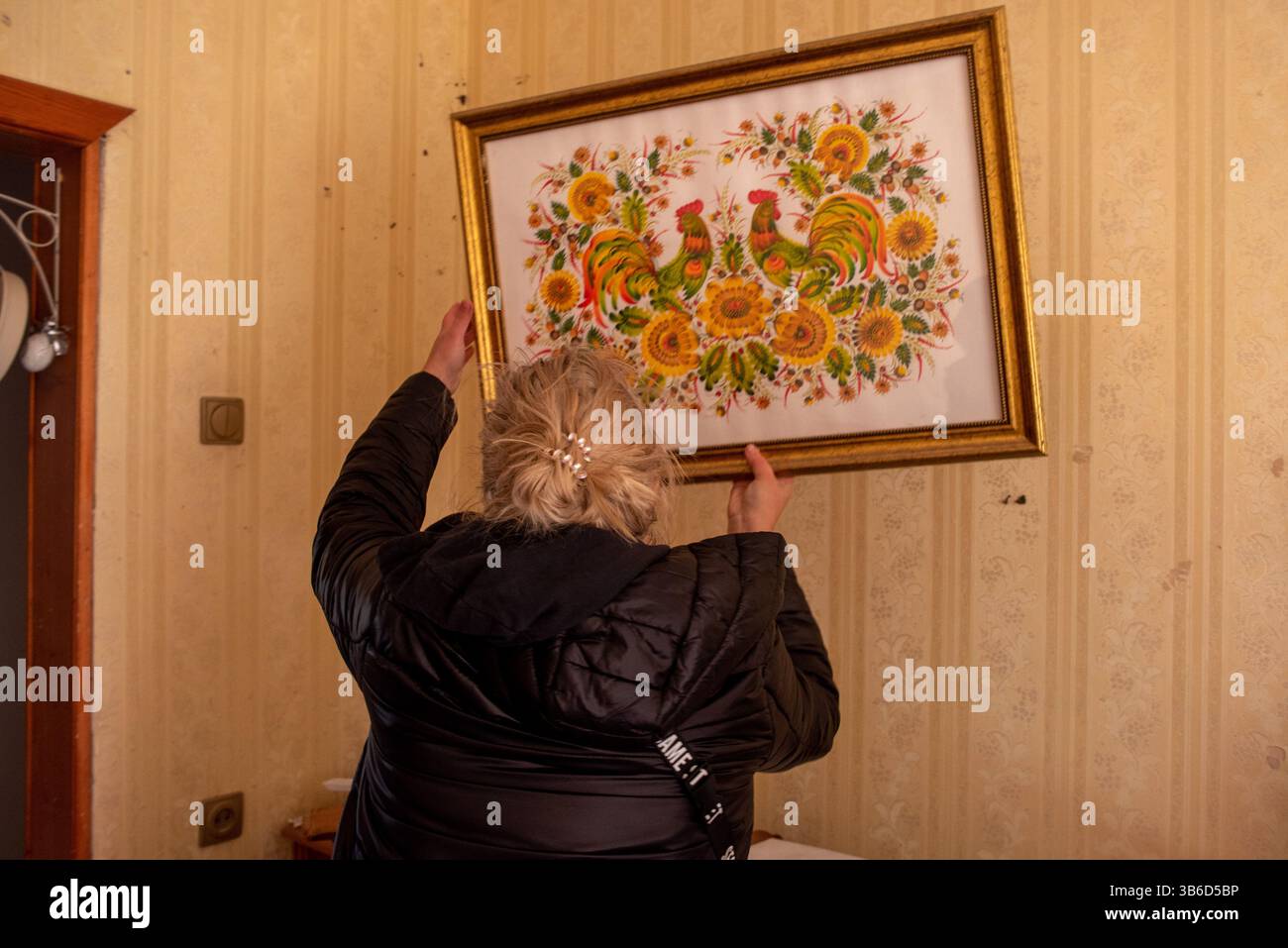 März 2022, Kiew, Ukraine: DARAYA IVANOVA, 40, eine Lehrerin für traditionelle ukrainische Volkskunst entfernt einen Rahmen aus ihrer zerstörten Wohnung, die von einem abgefangenen russischen Luftangriff in Kiew getroffen wurde. (Bild: © Seth Sidney Berry/ZUMA Press Wire Service) Stockfoto