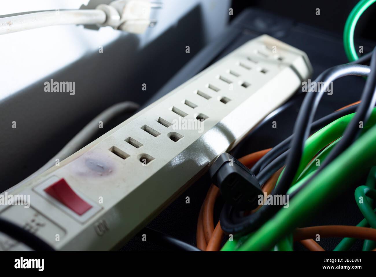 Eine Nahaufnahme einer Mehrfachsteckdose neben mehreren elektrischen Kabeln und Steckern. Stockfoto