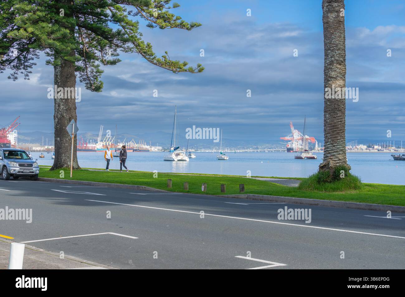 Tauranga Neuseeland - 26. Juni 2023; Blick von der Pilot Bay auf beide Seiten des Hafens von Tauranga Einrichtungen und Boote im Hafen mit Fußgängern auf dem Weg. Stockfoto