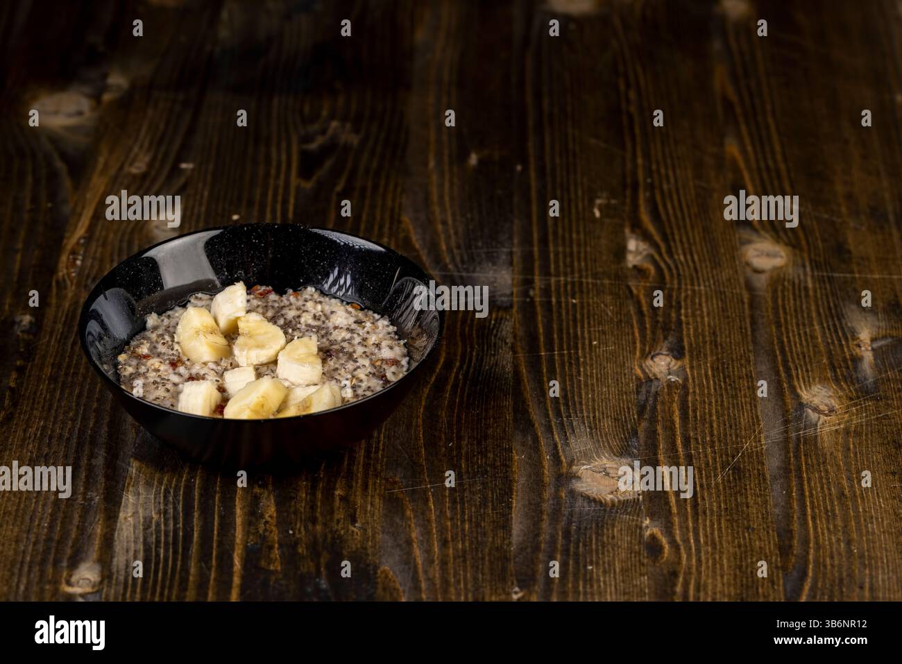 Fügen Sie reife Bananenstücke zum Brei hinzu, gekochten Haferbrei, Nahaufnahme Stockfoto
