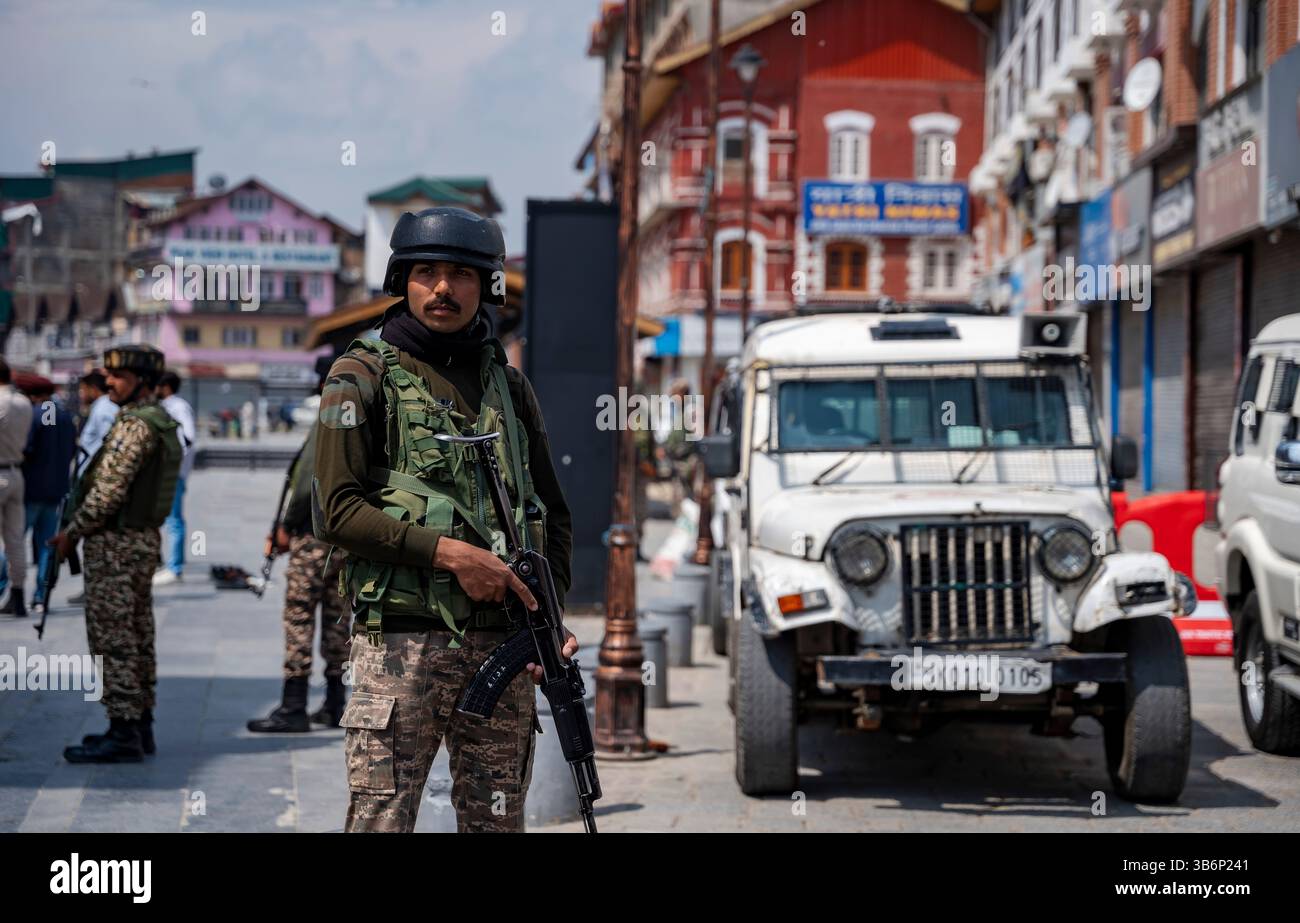 Indische Streitkräfte stehen vor einem gepanzerten Fahrzeug auf einer Straße in Srinagar Wache. Die Spannungen zwischen Indien und Pakistan haben sich nach einem militanten Angriff auf Kaschmirs Pahalgam am 22. April 2025 verschärft, bei dem 26 Tote starben und Berichten zufolge mit Pakistan in Verbindung stehen. Als Vergeltungsmaßnahme hat Indien strenge Maßnahmen ergriffen, darunter das Verbot pakistanischer Schiffe, die Aussetzung des Indus-Wasserabkommens, die Einstellung aller Importe und die Annullierung von Visa für pakistanische Staatsangehörige. Mit zunehmender Feindseligkeit droht ein begrenzter Konflikt, der die Aufmerksamkeit darauf lenkt, wie Nachbarländer wie China, Sri Lanka, Nepal, Malediven, A Stockfoto