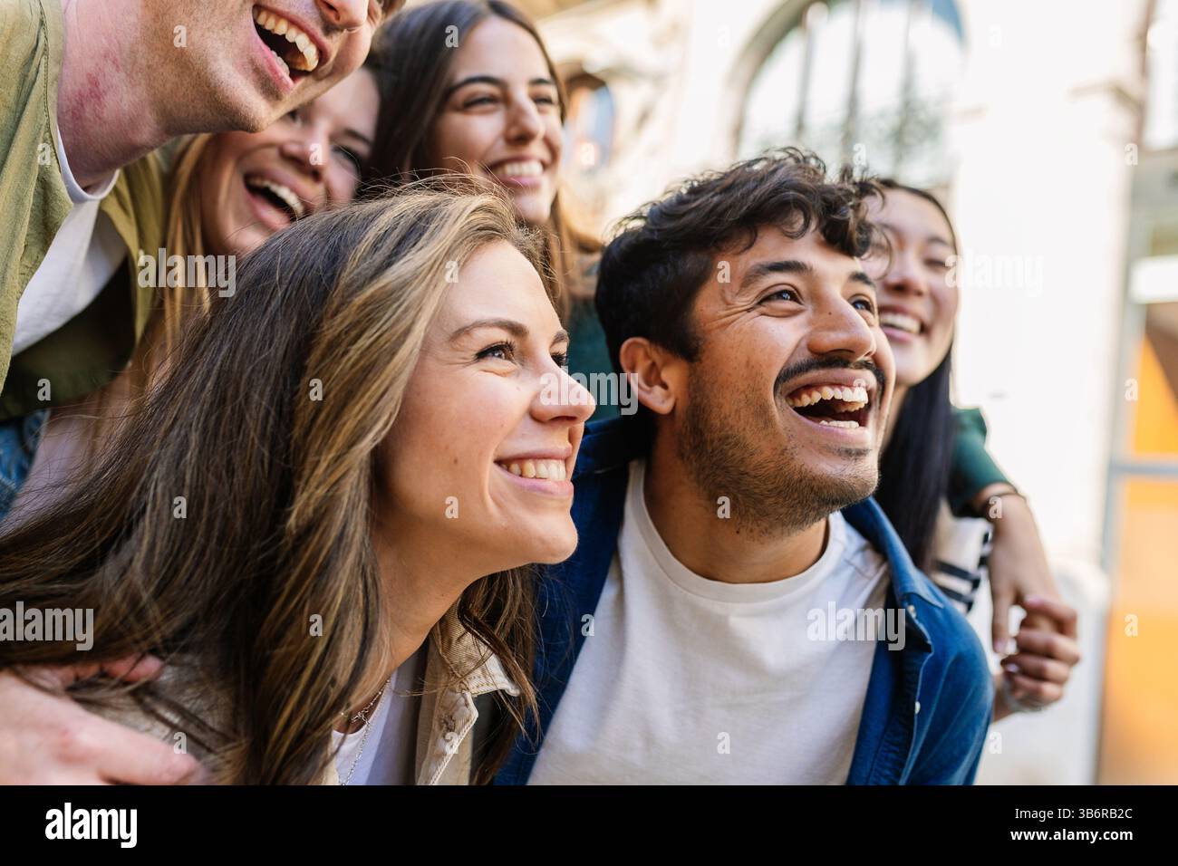 Glückliche Gruppe junger Studenten, die sich umarmen und draußen lachen. Stockfoto