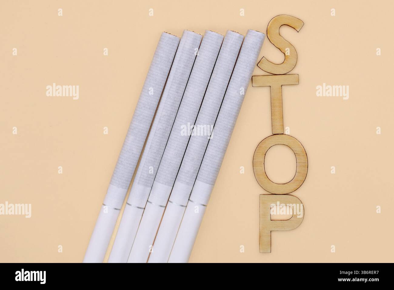 Zigaretten sind neben hölzernen Buchstaben angeordnet, die das Wort „Stop“ beschreiben, was das Bewusstsein gegen das Rauchen und die Gesundheitsfürsorge symbolisiert. Stockfoto