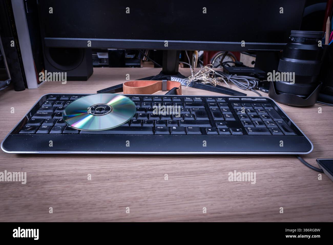 Auf einer Computertastatur liegende CD, die eine Datenübertragung oder Softwareinstallation in einer Retro-Tech-Umgebung vorschlägt Stockfoto