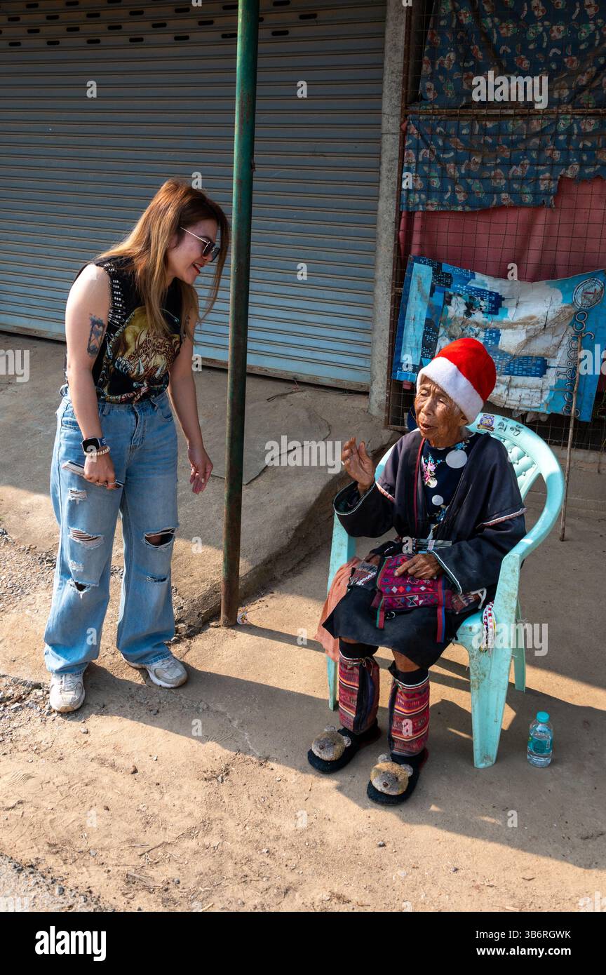 Eine junge Thai-Frau, die sich kurz in ihrer eigenen Sprache unterhalten und sich mit einer älteren Dame unterhalten, die in ihrer eigenen Stammessprache spricht, in einer Chr Stockfoto