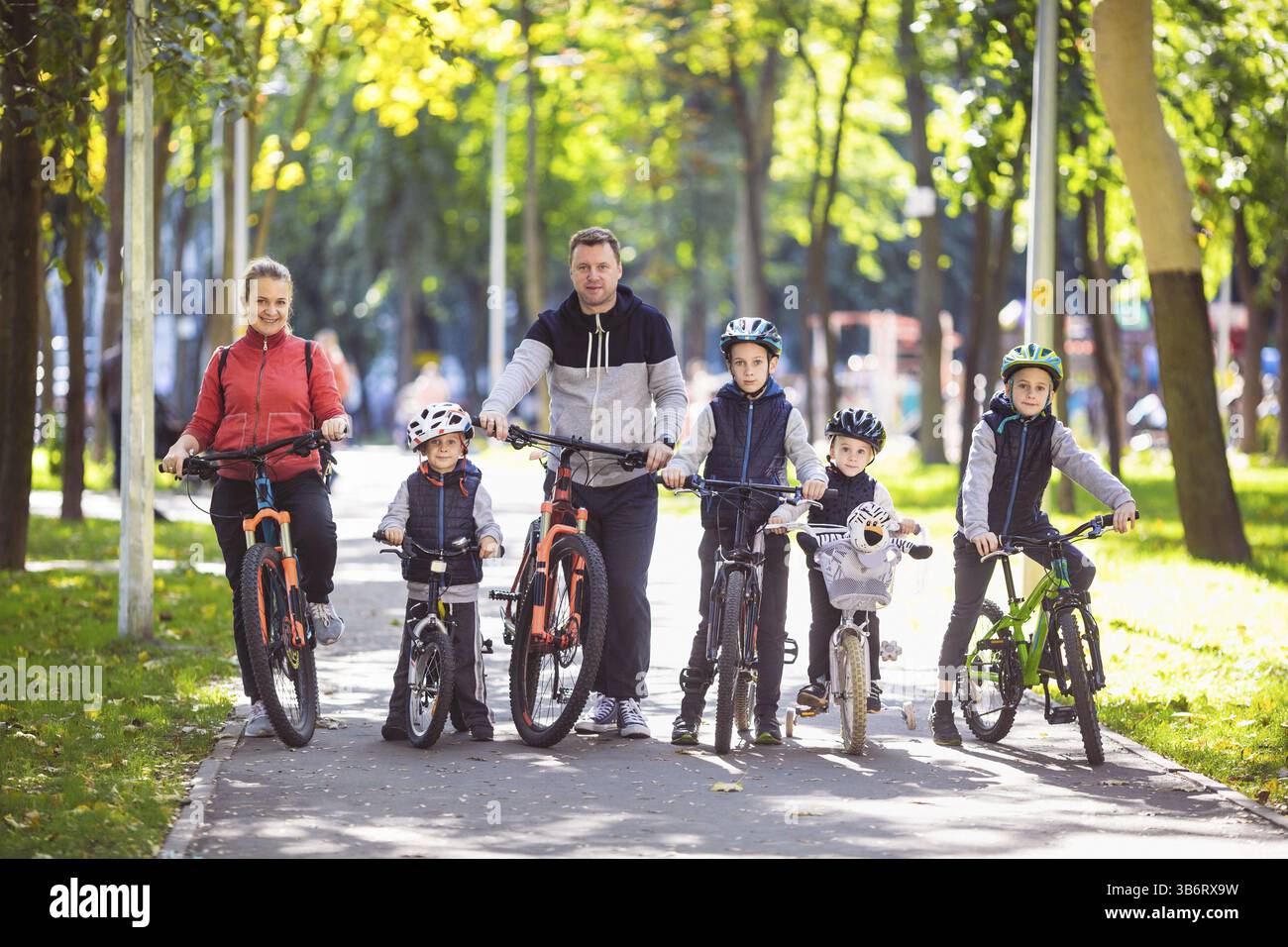 Thema Familie Sport aktiv Erholung im Freien. Eine Gruppe von Menschen ist eine große Familie von 6 Personen stehen auf Mountainbikes in einem Stadtpark auf einer Roa posing Stockfoto