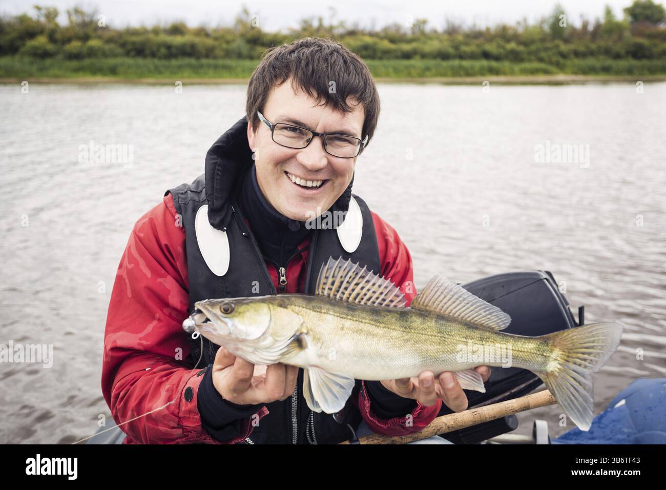 Mittelerwachsener Fischer im Urlaub auf dem Fluss, entspannen und Forellen angeln. Konzentrieren Sie sich auf fisher Stockfoto
