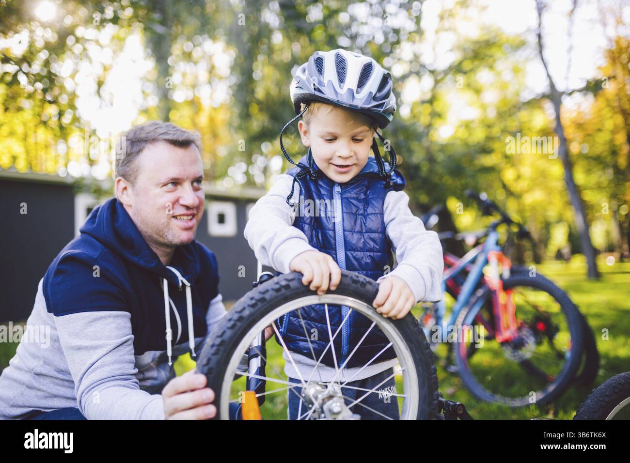 Vatertag kaukasischen Papa und unseren 5 Jahre alten Sohn im Hinterhof in der Nähe des Hauses auf dem grünen Rasen auf dem Rasen Reparatur Fahrrad, pumpt ein Fahrrad whe Stockfoto