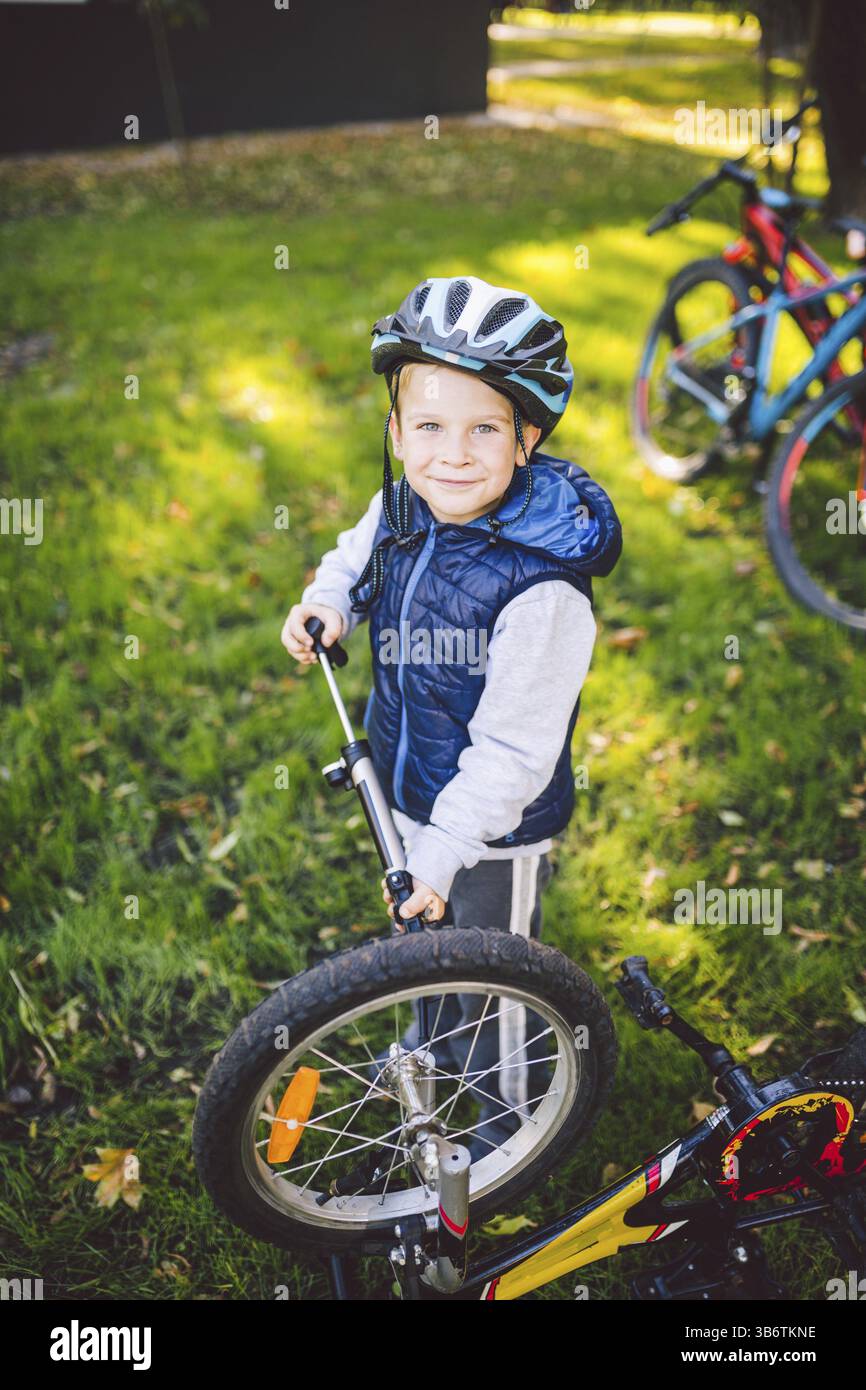 Aktive Freizeit für Kinder im Park. Ein Kind studiert den Mechanismus eines Mountainbikes. Kleinkind repariert ein Fahrrad im Wald. Fahrradclub für c Stockfoto