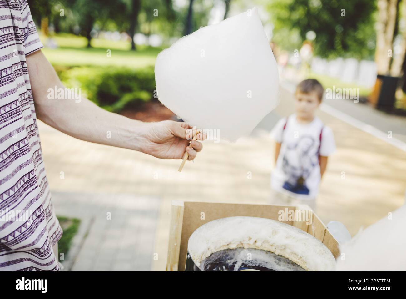 Das Thema ist ein kleines Familienunternehmen, das Süßigkeiten kocht. Ein junger männlicher Ladenbesitzer, der einen Händler hält, macht Süßigkeiten-Floß, Feenfloß oder Cotton Cand Stockfoto