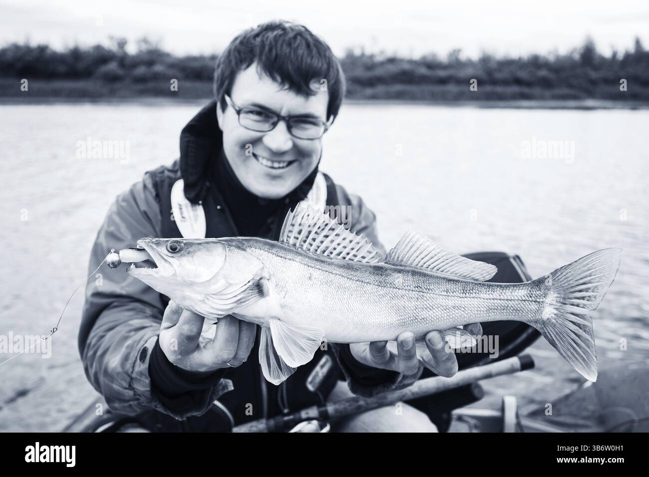 Mittelerwachsener Fischer im Urlaub auf dem Fluss, entspannen und Forellen angeln. Konzentrieren Sie sich auf fisher Stockfoto