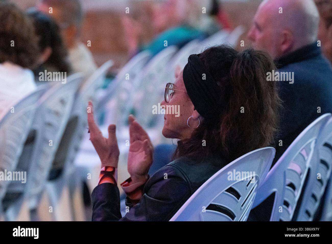 Frau in einer Reihe von Sitzen applaudiert, Konzertverse und Musik, „Nuredduna“ von Miquel Costa i Llobera, „La deixa del geni grec“, Coves d'Artà, Mallorca, Stockfoto