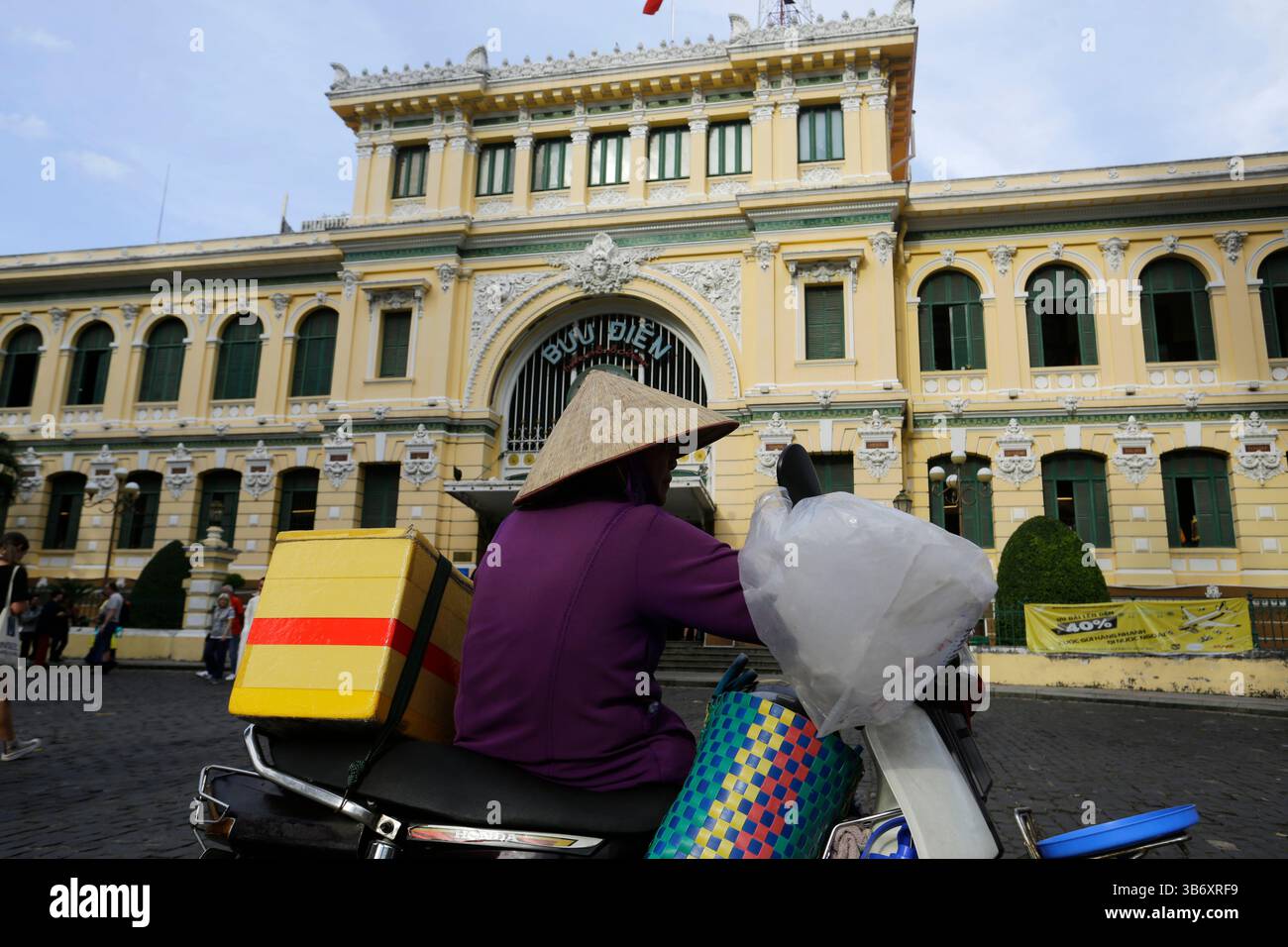 Ho-Chi-Minh-Stadt, Vietnam - 3. Januar 2023: Vietnamesischer Street-Food-Händler mit traditionellem konischem Hut, Non La, im zentralen Postamt von Saigon. Stockfoto