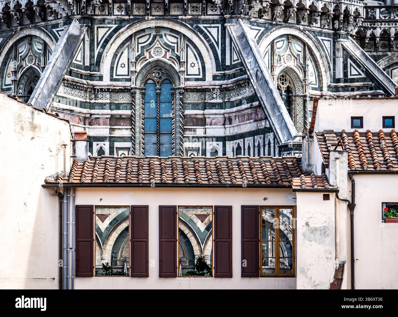 Eine Nahaufnahme der architektonischen Details mit komplexen Mustern und Entwürfen eines historischen Gebäudes, mit einer Reflexion im Fenster eines nahegelegenen Stockfoto