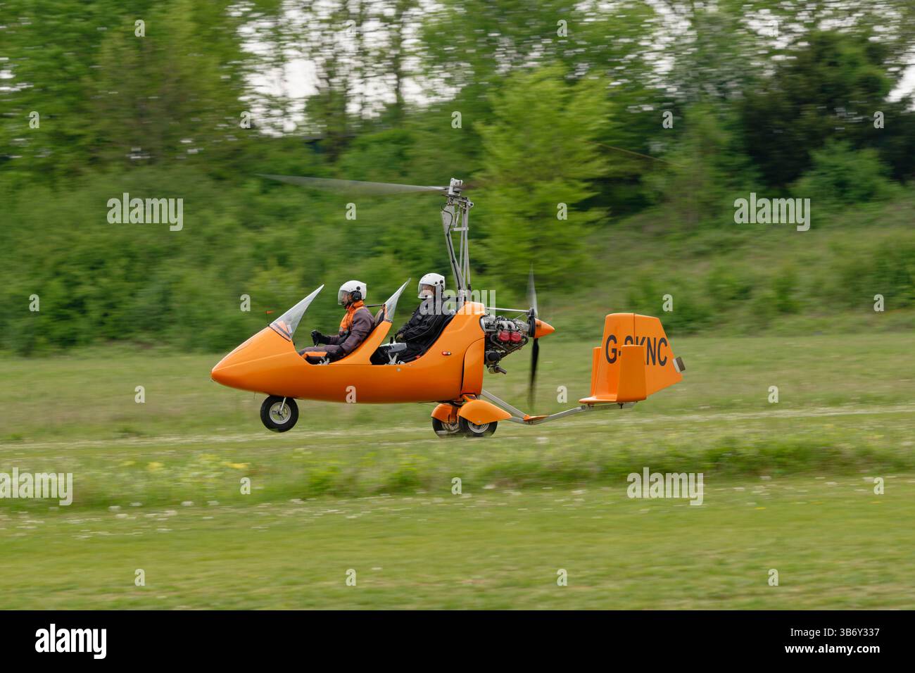 Der Smart Orange Tandem Seat Autogyro MTOsport G-SKNC kommt auf dem Popham Airfield in Hampshire, England, an der jährlichen Microlight Fly-in and Fair vorbei Stockfoto