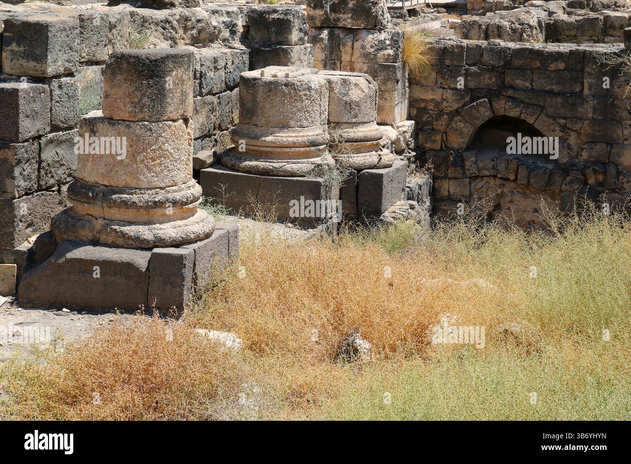 Steinsäulenbasen und römische Mauerwerke an der archäologischen Stätte Beit She’an in Israel, die Basaltblöcke und verwitterten Kalkstein zeigen. Stockfoto