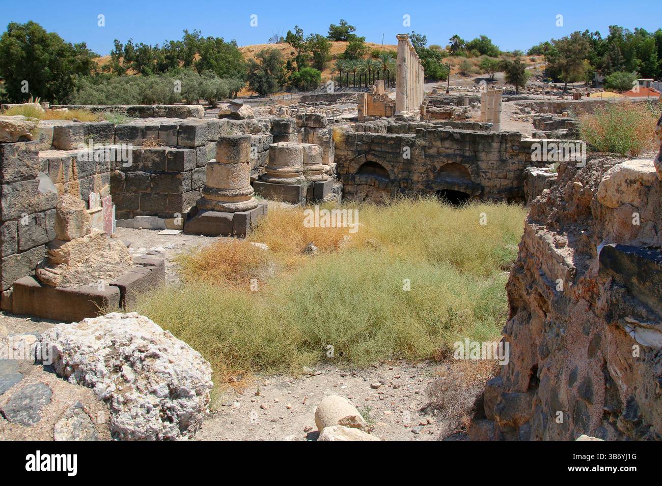 Steinsäulenbasen und römische Mauerwerke an der archäologischen Stätte Beit She’an in Israel, die Basaltblöcke und verwitterten Kalkstein zeigen. Stockfoto