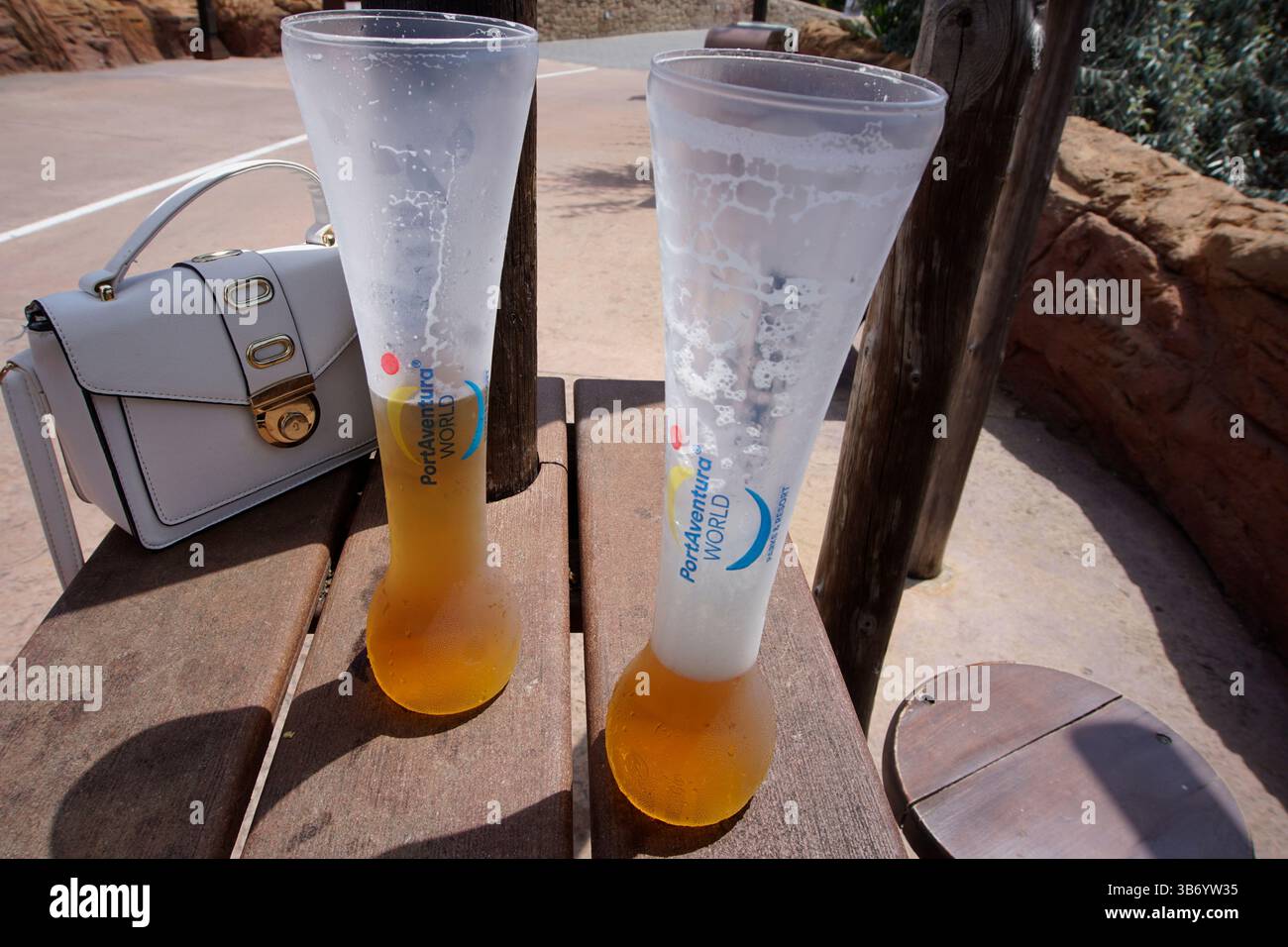 Halbfertige Getränke in hohen Bechern mit PortAventura World auf einer Holzbank, La Pineda, Spanien, während eines Sommerurlaubs. Salou, Spanien Stockfoto