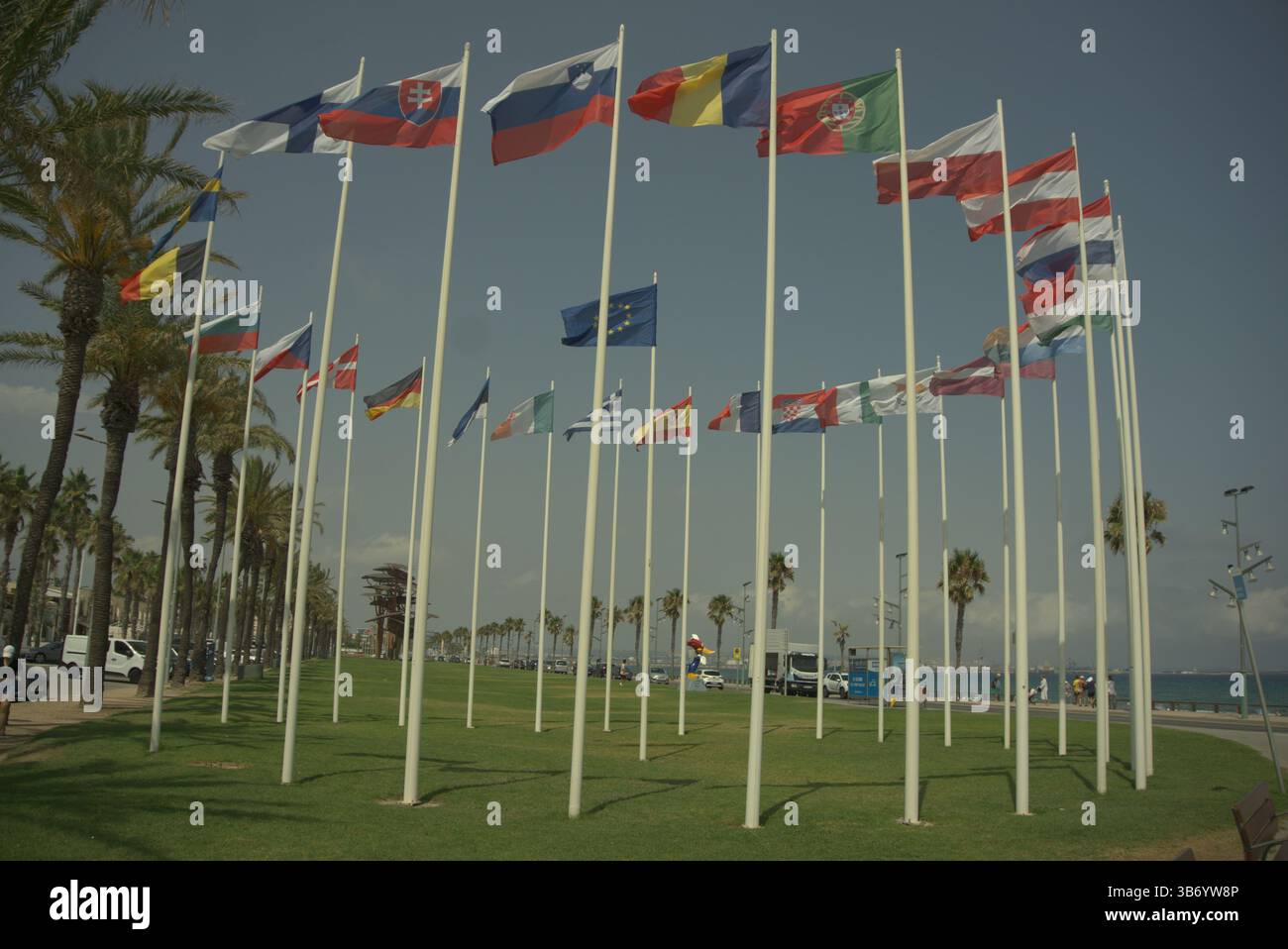 Europäische und internationale Flaggen winken in der Meeresbrise entlang der Küstenpromenade von La Pineda, Spanien. Salou, Spanien Stockfoto