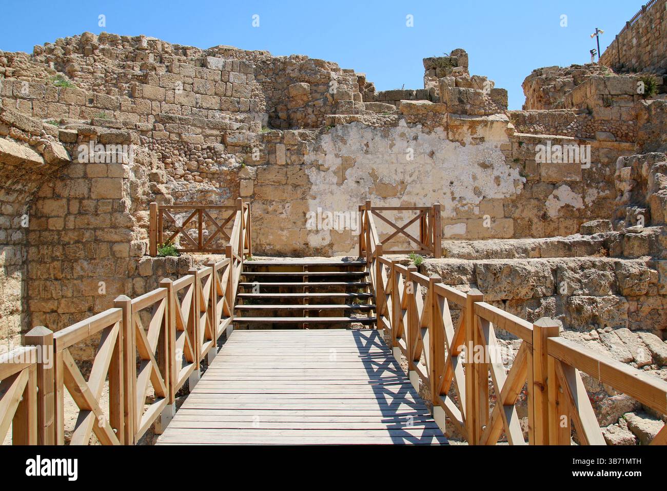 Steinbau aus römischer Zeit in Caesarea Maritima, Israel, mit einem hölzernen Fußweg für Besucher zwischen den archäologischen Ruinen. Stockfoto