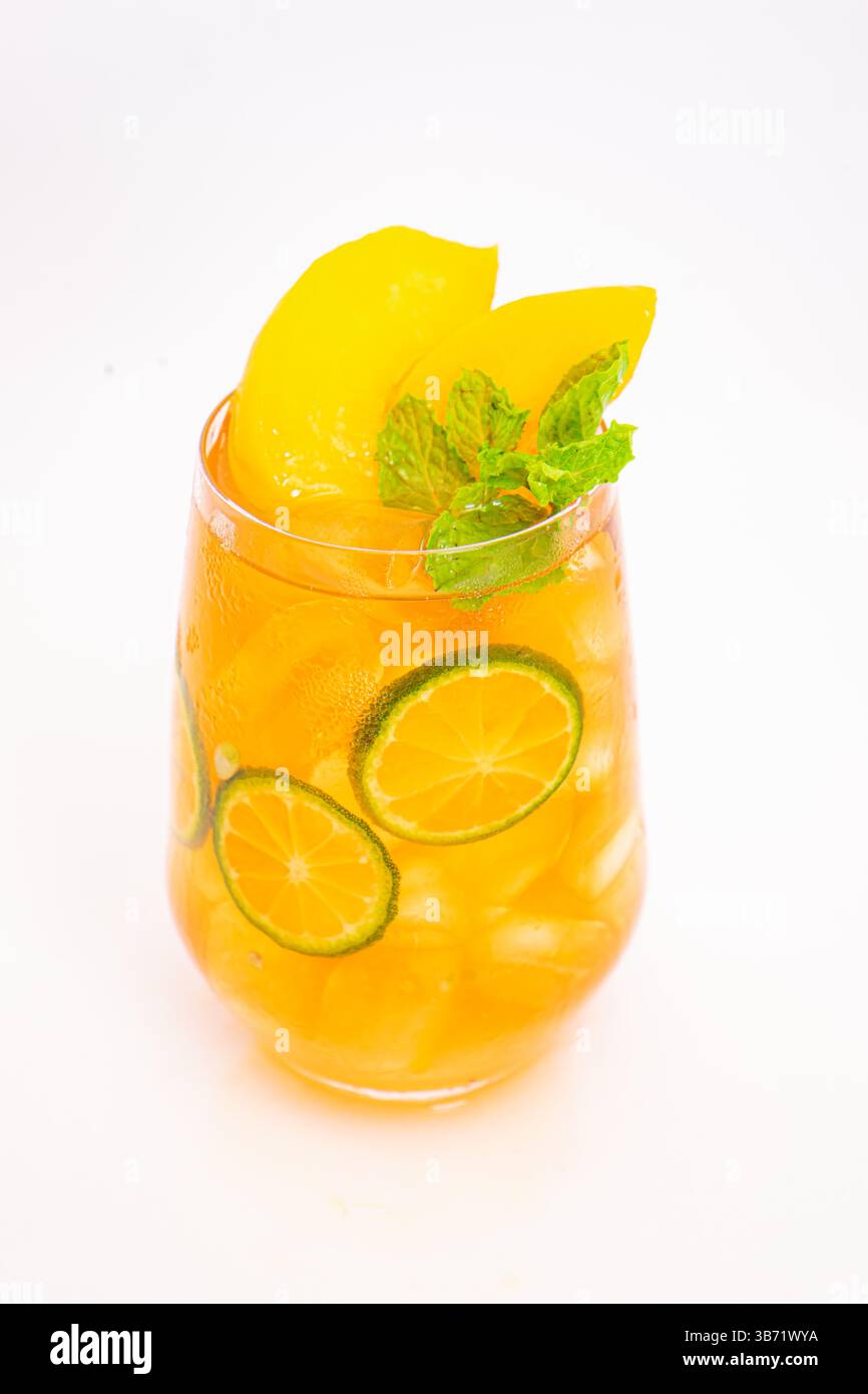 Gelbes Pfirsich- und orangenes Zitrusgetränk mit frischen Minzblättern und Eis serviert in klarem Glas auf weißem Hintergrund. Hochwertige Fotos Stockfoto