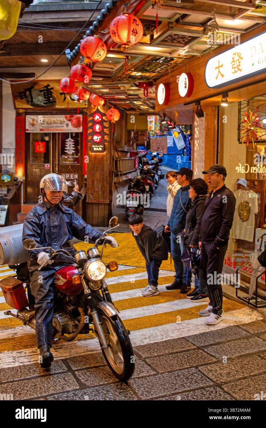 Ein Motorrad durchquert die geschäftige Jiufen Old Street Stockfoto