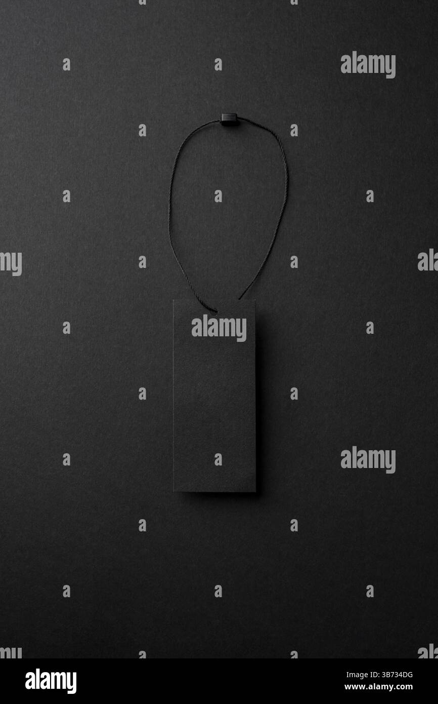 Leerer schwarzer Pappanhänger mit Schnur auf schwarzem Hintergrund Stockfoto