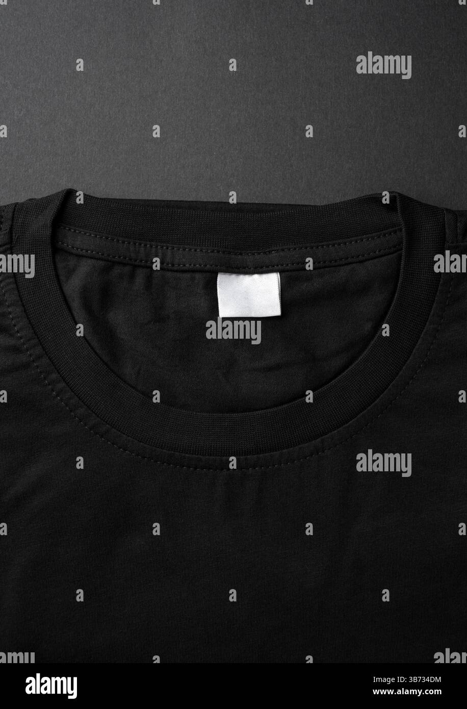 Nahaufnahme des schwarzen T-Shirt-Kragens mit leerem weißem Etikett Stockfoto