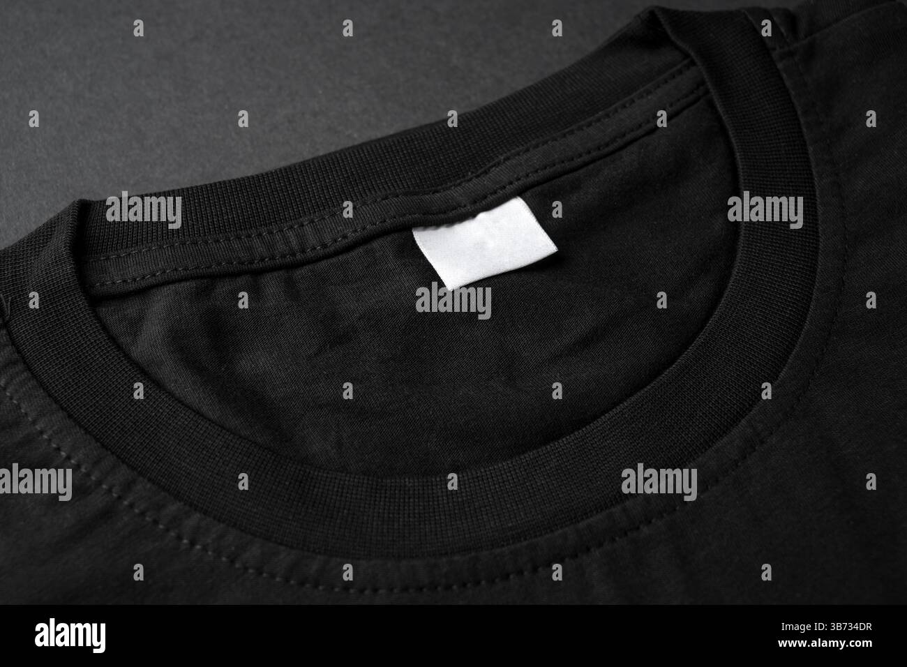 Nahaufnahme des schwarzen T-Shirt-Kragens mit leerem weißem Etikett Stockfoto