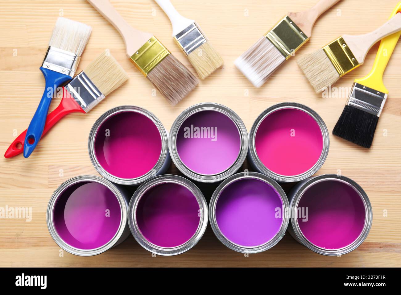 Dosen mit Farbe in Violett und Pinsel auf hölzernem Hintergrund, Draufsicht Stockfoto