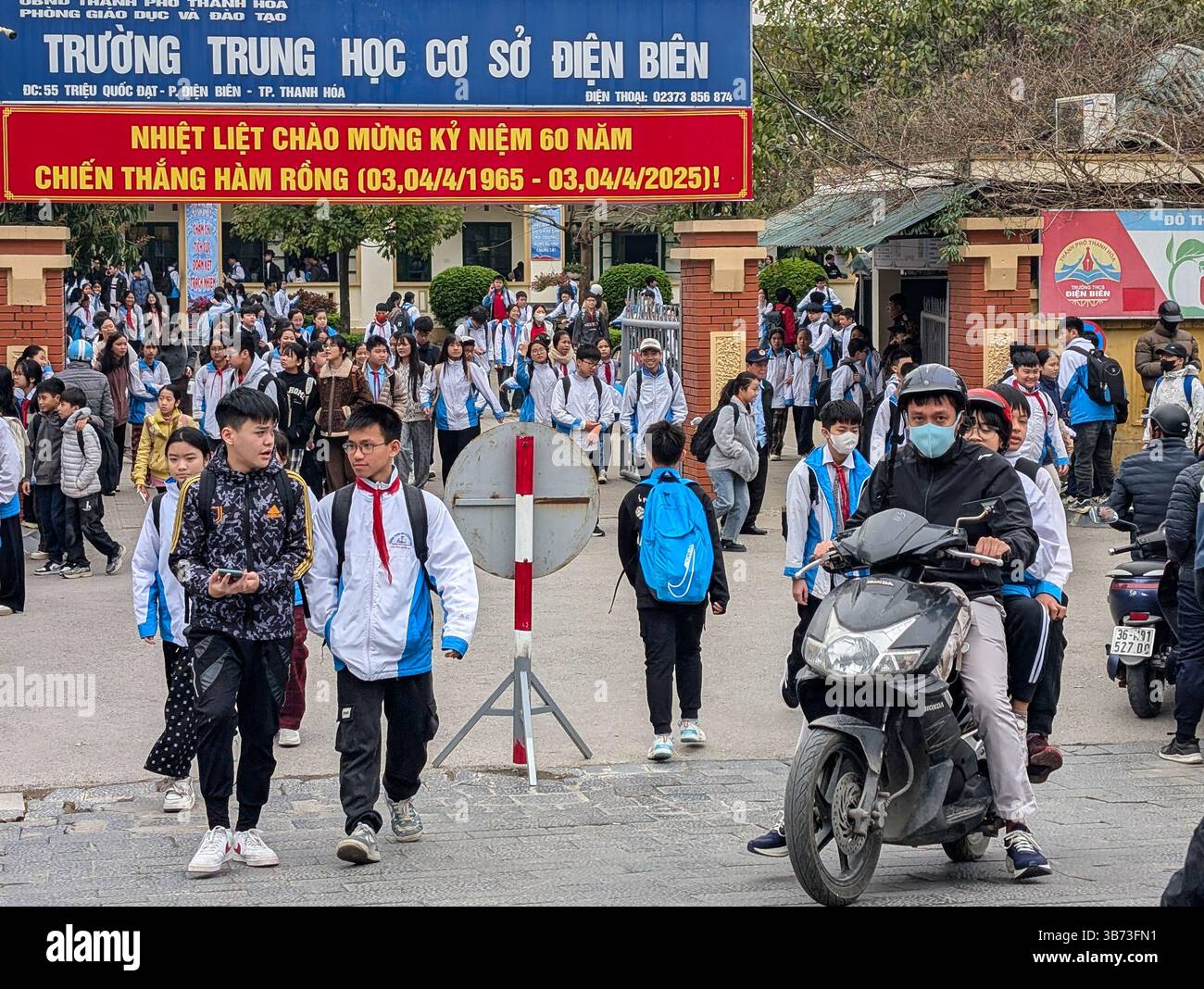 Schüler einer Mittelschule in Thanh Hoa, Vietnam, verlassen am 18. März 2025 ihre Schule nach dem Unterricht. Die Schüler tragen weiße und blaue Uniformen. Stockfoto